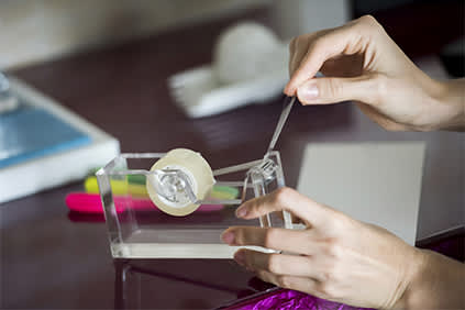女人服用从Scotch胶带分配器一片透明胶带。