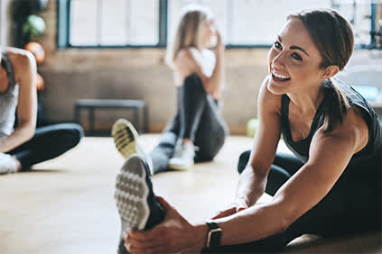 微笑的女人在健身房伸展。