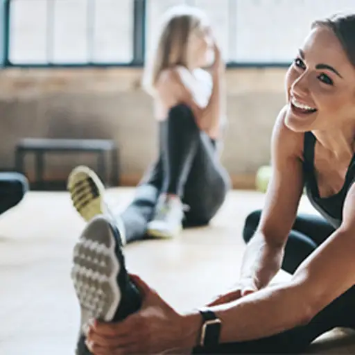 微笑的女人在健身房里伸懒腰。