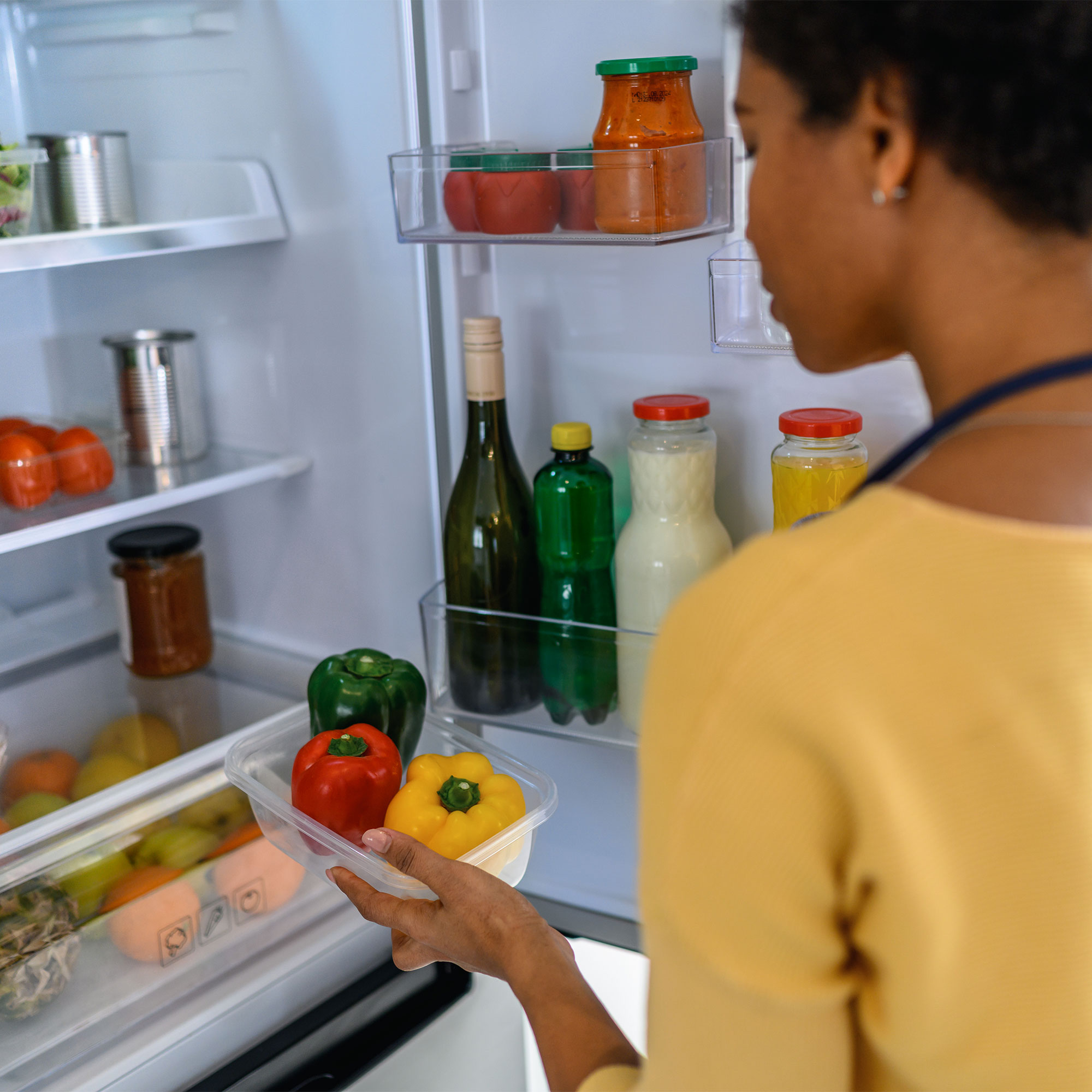 一个女人看着她的冰箱里面