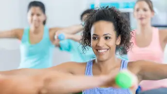 Smiling woman in group exercise class with hand weights.