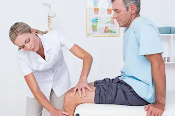 Physical Therapist examines mans knee