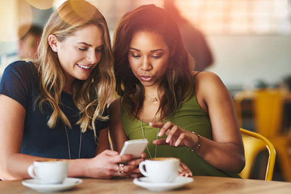 妇女在咖啡馆寻找一个手机应用程序一起。