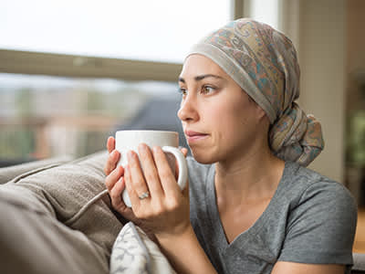 民族年轻女子在沙发上喝茶的癌症饮水杯