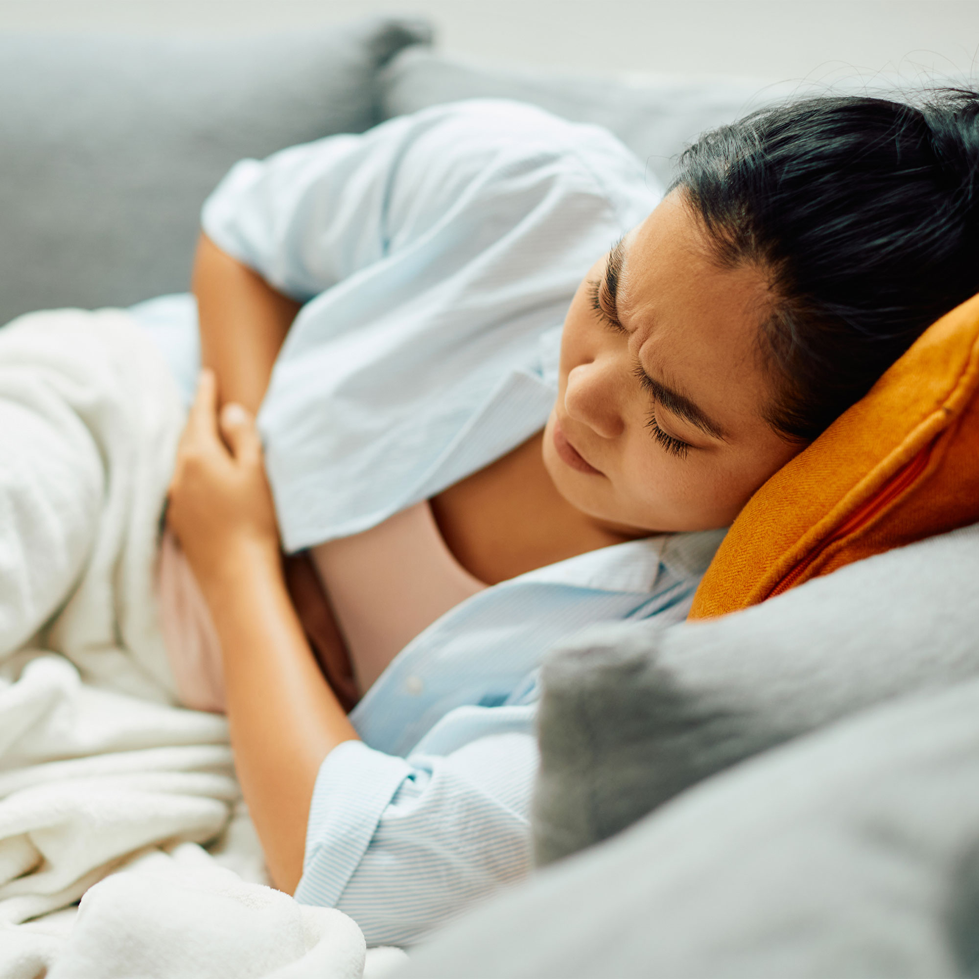 一个女人躺在沙发上,触动她的腹部疼痛