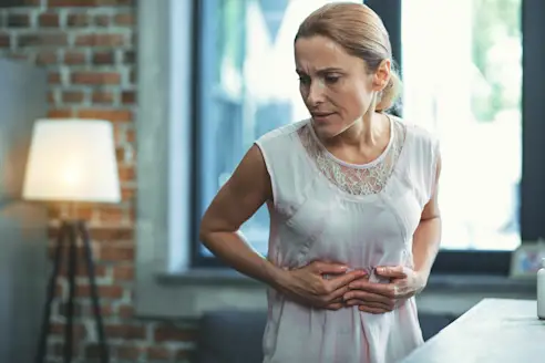A woman touches her stomach in pain
