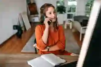 A woman looks at her computer while talking on the phone