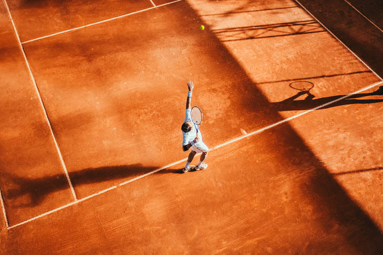 头顶上的人在红土球场打网球。