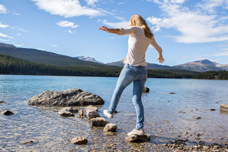 年轻女子步行从石头石头在水中。