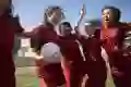 A group of teenage girls celebrate after winning a soccer match.