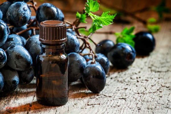 葡萄籽油在棕色的瓶子，串葡萄，葡萄