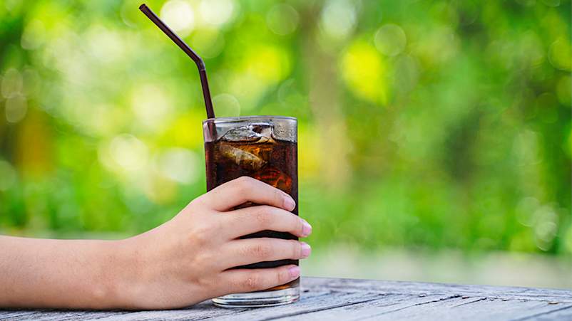 拿着一杯用吸管喝的苏打水的女人。