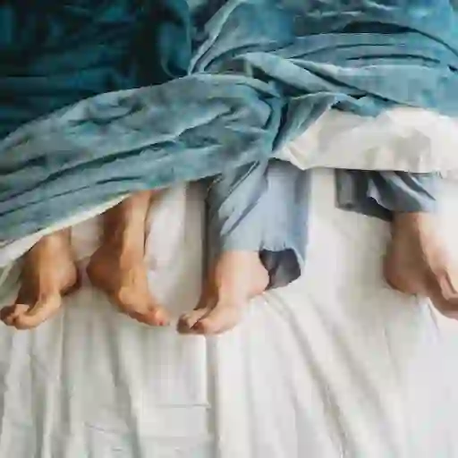 一对夫妻躺在床上，他们的脚从床单下伸出来。