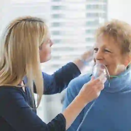 照顾者帮助高级女人一个氧气面罩。