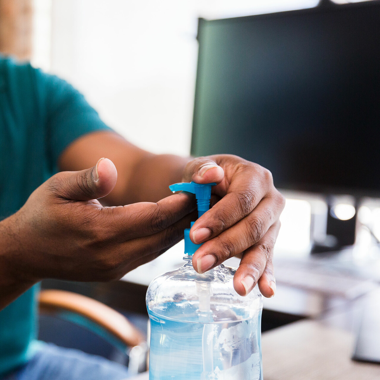 一名男子在他的办公桌上使用洗手液