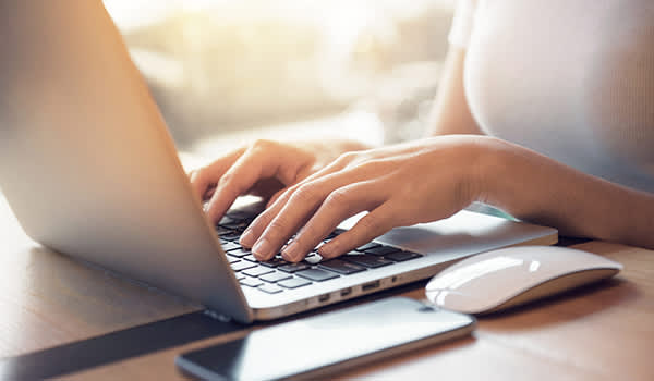 女人的双手打字的笔记本电脑。