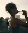 一个迷人的年轻女子戴着耳机在城市晨跑后喝水的短镜头