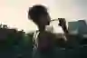 一个迷人的年轻女子戴着耳机在城市晨跑后喝水的短镜头
