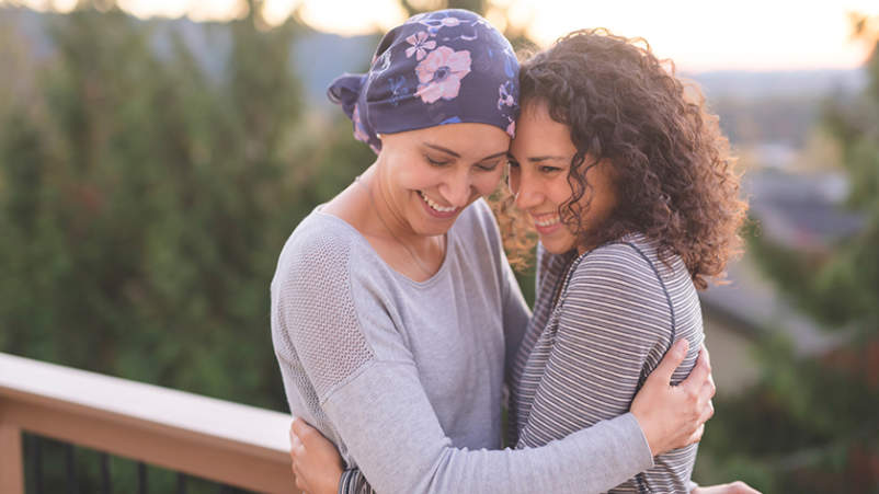 女子与癌症微笑和拥抱她的朋友。