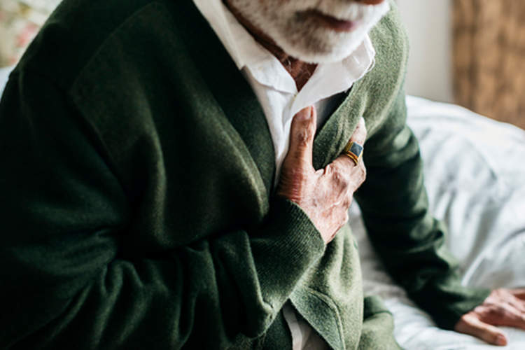 胸部疼痛的老人坐在床上。