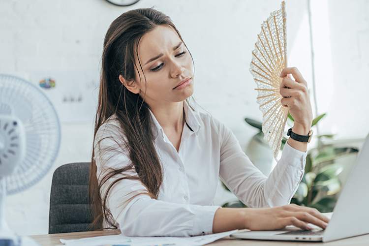 Overheated woman fanning herself at work.