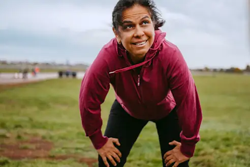A woman takes a break from exercising outside