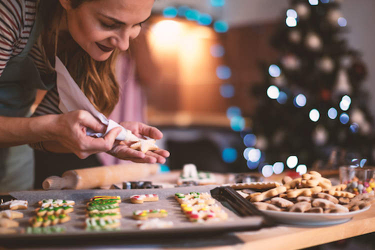 女人在节日饼干上撒糖霜。