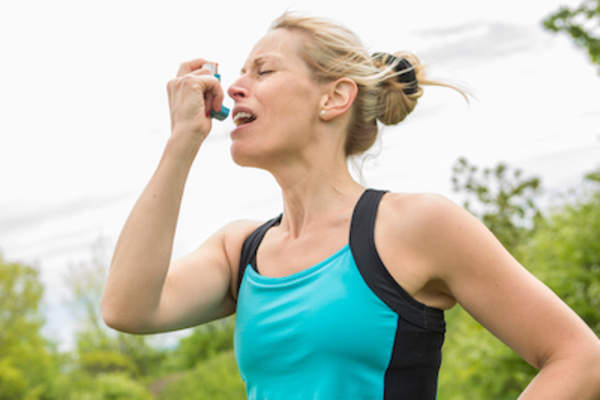 妇女在跑步时使用吸入器。