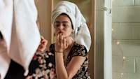 Woman applying makeup with towel wrapped around her head
