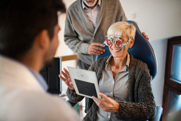 高级的女人有她的视力在眼科医生的办公室年轻眼科医生检查