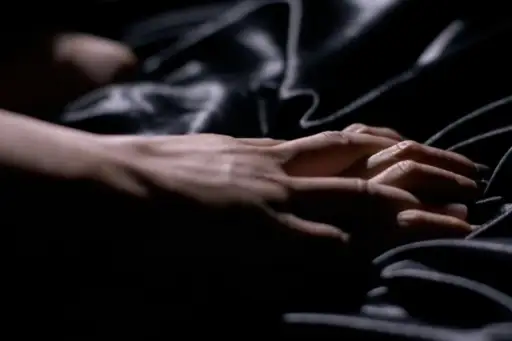夫妇俩的手紧握着黑色缎子床单