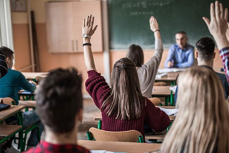 学生提高他们的手在一个高中班。