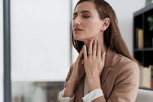 喉咙痛的女人触摸她的脖子。