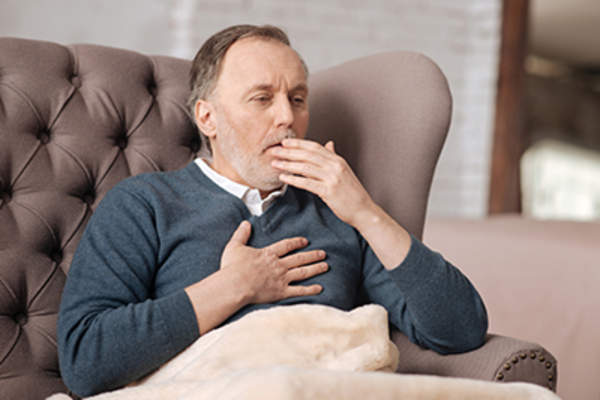 老人坐在沙发上咳嗽