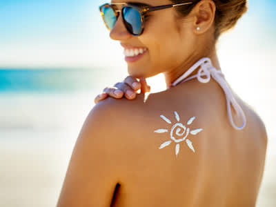 在海滩上的女人，肩膀被防晒霜晒伤。