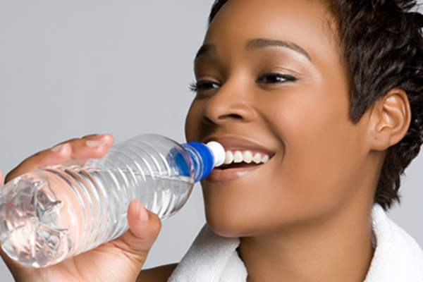 Pretty young woman drinking from water bottle.