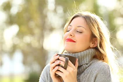 一个心满意足的女人在外面端着一杯咖啡。