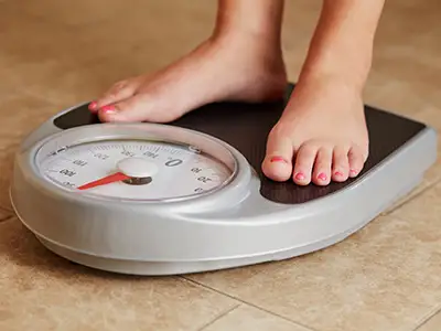 一位妇女站在秤上检查体重。
