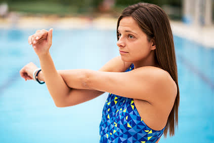 游泳前伸展身体的年轻女子。