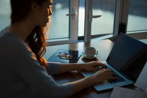 日落在计算机上工作的女人
