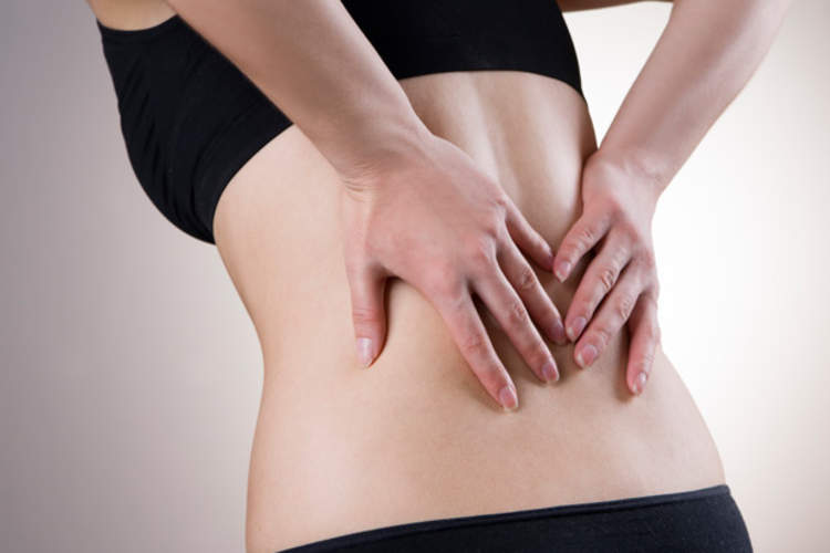 女子抱着坐骨神经痛疼痛腰部。