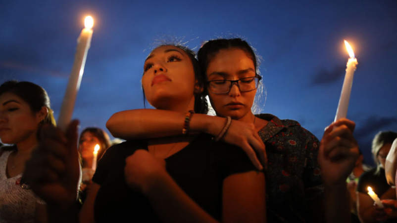 人们出席于2019年8月7日一传射在得克萨斯州埃尔帕索的临时纪念碑表彰遇难者烛光守夜活动。