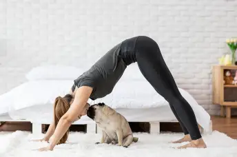一个女人在和她的哈巴狗做瑜伽