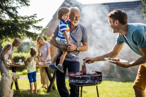 快乐的爷爷和孙子和正在后院准备烧烤的年轻父亲交谈