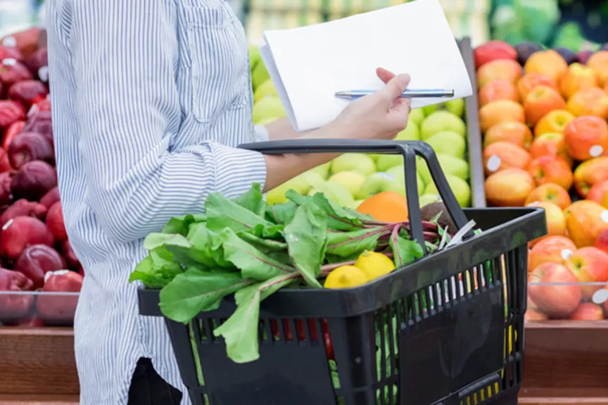 女人拿着购物单去买农产品。