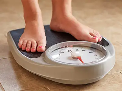 女性脚在体重秤上。
