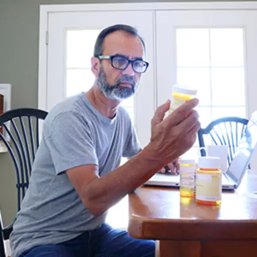 看处方药瓶的人在家。