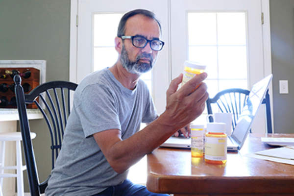 男子看着处方药瓶子在家里。