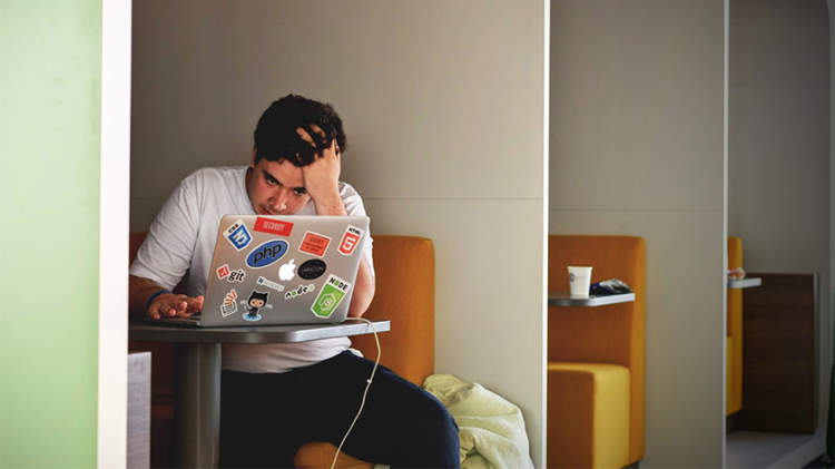 一个用笔记本电脑工作的精疲力竭的年轻人。