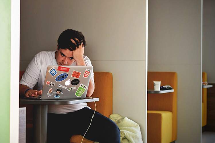 一个用笔记本电脑工作的精疲力竭的年轻人。